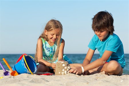 simsearch:400-04423521,k - Kids playing on the beach building a sand castle decorating it with seashells Photographie de stock - Aubaine LD & Abonnement, Code: 400-07091053