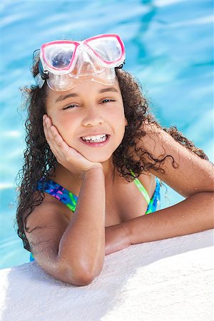 A cute happy young interracial African American girl child relaxing on the side of a swimming pool smiling & wearing pink goggles Stock Photo - Budget Royalty-Free & Subscription, Code: 400-07116586