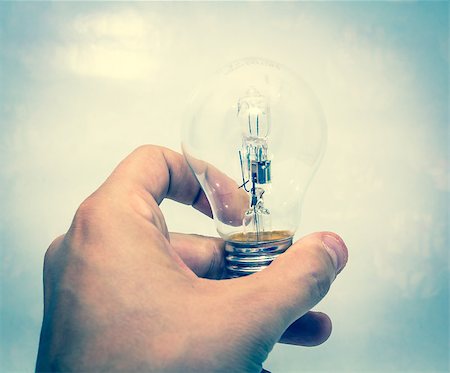 A hand holding a lightbulb against blue background Stock Photo - Budget Royalty-Free & Subscription, Code: 400-07112237