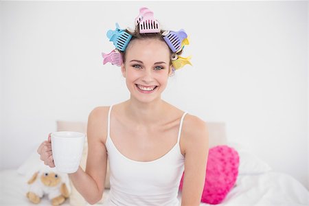 simsearch:400-07129766,k - Joyful natural brown haired woman in hair curlers holding a cup of coffee in bright bedroom Stock Photo - Budget Royalty-Free & Subscription, Code: 400-07129723