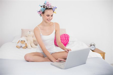 simsearch:400-07129766,k - Happy natural brown haired woman in hair curlers using a laptop in bright bedroom Stock Photo - Budget Royalty-Free & Subscription, Code: 400-07129736