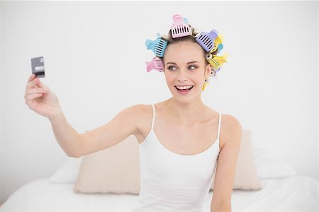 simsearch:400-07129766,k - Excited natural brown haired woman in hair curlers holding a credit card in bright bedroom Stock Photo - Budget Royalty-Free & Subscription, Code: 400-07129741