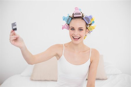 simsearch:400-07129766,k - Content natural brown haired woman in hair curlers holding a credit card in bright bedroom Stock Photo - Budget Royalty-Free & Subscription, Code: 400-07129742