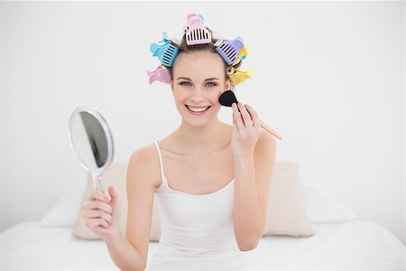 simsearch:400-07129766,k - Joyful natural brown haired woman in hair curlers applying powder on her face in bright bedroom Stock Photo - Budget Royalty-Free & Subscription, Code: 400-07129754