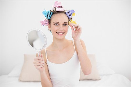 simsearch:400-07129766,k - Amused natural brown haired woman in hair curlers plucking her eyebrows in bright bedroom Stock Photo - Budget Royalty-Free & Subscription, Code: 400-07129766