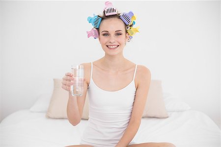 simsearch:400-07129766,k - Cheerful natural brown haired woman in hair curlers holding a glass of water in bright bedroom Stock Photo - Budget Royalty-Free & Subscription, Code: 400-07129771