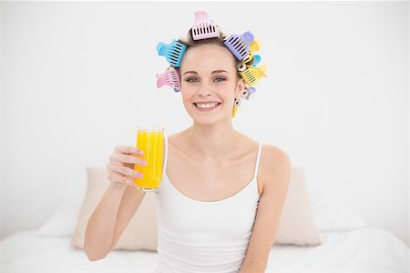 simsearch:400-07129766,k - Charming natural brown haired woman in hair curlers holding a glass of orange juice in bright bedroom Stock Photo - Budget Royalty-Free & Subscription, Code: 400-07129773