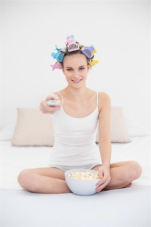 simsearch:400-07129766,k - Concentrated natural brown haired woman in hair curlers watching tv while eating popcorn in bright bedroom Stock Photo - Budget Royalty-Free & Subscription, Code: 400-07129785