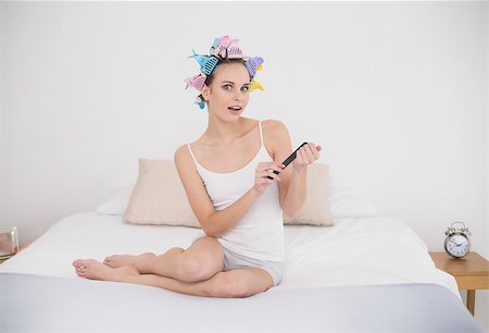 simsearch:400-07129766,k - Surprised natural brown haired woman in hair curlers filing her nails in bright bedroom Stock Photo - Budget Royalty-Free & Subscription, Code: 400-07129795