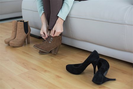 simsearch:6109-07497438,k - Young slender woman tying her shoelaces sitting on couch Stock Photo - Budget Royalty-Free & Subscription, Code: 400-07133084