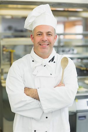 Mature head chef smiling at camera holding a wooden spoon Stock Photo - Budget Royalty-Free & Subscription, Code: 400-07140070