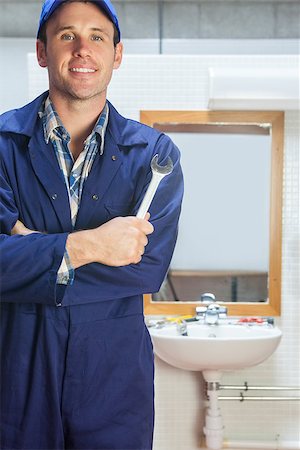 pipe wrench - Smiling plumber posing with wrench in public bathroom Stock Photo - Budget Royalty-Free & Subscription, Code: 400-07141277