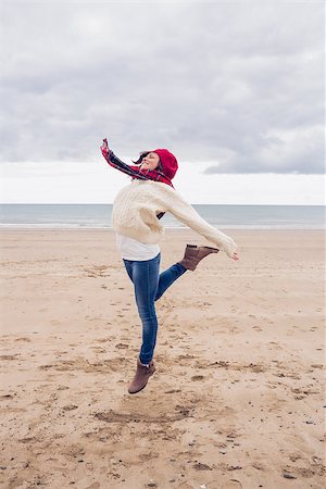 simsearch:400-07181052,k - Full length of a woman in stylish warm clothing jumping at the beach Stock Photo - Budget Royalty-Free & Subscription, Code: 400-07142251