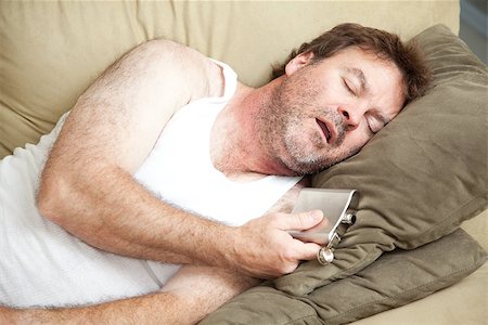 Unemployed man passed out drunk on the couch with a flask of booze in his hand. Stock Photo - Budget Royalty-Free & Subscription, Code: 400-07165102