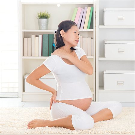 Shoulder or neck pain. Eight months pregnant Asian woman holding her back and shoulder while sitting on a floor at home. Stock Photo - Budget Royalty-Free & Subscription, Code: 400-07167246