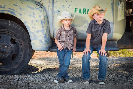 Two Young Boys Wearing Cowboy Hats Leaning Against an Antique Truck in a Rustic Country Setting. Stock Photo - Budget Royalty-Free & Subscription, Code: 400-07179043
