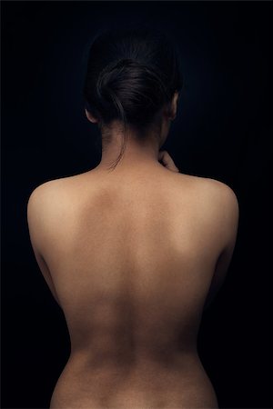 Young indian woman showing her smooth skinned back and black background Stock Photo - Budget Royalty-Free & Subscription, Code: 400-07179199