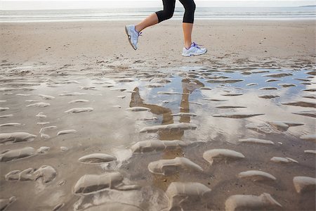 simsearch:400-04535435,k - Low section of a healthy young woman jogging on shore at beach Stock Photo - Budget Royalty-Free & Subscription, Code: 400-07180899