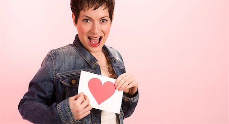 A pretty woman against pink hold her valentine's card with a heart on it Stock Photo - Budget Royalty-Free & Subscription, Code: 400-07208640