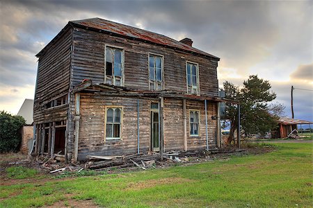 A dilapidated two storey late Victorian Georgian farm house with corrugated iron roof with attic space and corbelled brick fireplace,  no longer lived in.  It once had an upper storey verandah with fancy wrought iron lattice work.  It lies between the Hawkesbury river and the plains of Freeman's Reach. The house has survived many hardships including floods. It would have been beautiful in its day, Stock Photo - Budget Royalty-Free & Subscription, Code: 400-07223800