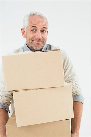 simsearch:400-07930718,k - Portrait of a smiling mature man carrying boxes against white background Stock Photo - Budget Royalty-Free & Subscription, Code: 400-07230870