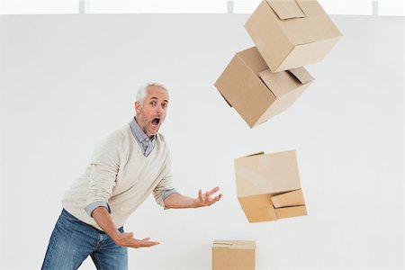 simsearch:400-07930718,k - Side view of a mature man with falling boxes against white background Stock Photo - Budget Royalty-Free & Subscription, Code: 400-07230872