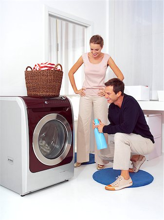 simsearch:400-07902993,k - Man puts clothes into the washing machine while woman smiling Photographie de stock - Aubaine LD & Abonnement, Code: 400-07244398