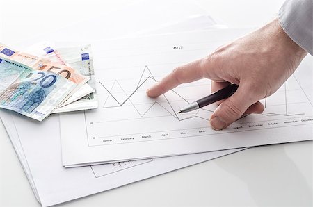 Cropped view of a man pointing at financial report with Euro money on a table. Stock Photo - Budget Royalty-Free & Subscription, Code: 400-07249748