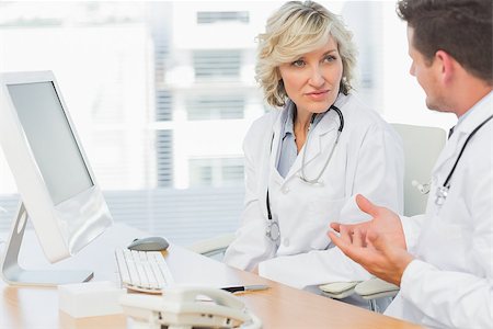 Two concentrated doctors discussing something by computer at medical office Stock Photo - Budget Royalty-Free & Subscription, Code: 400-07274776