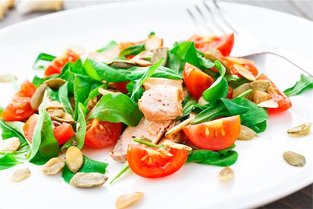 Salad with arugula, salmon, cherry tomato and pumpkin seeds on a plate Stock Photo - Budget Royalty-Free & Subscription, Code: 400-07301666