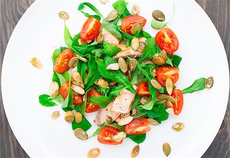 Salad with arugula, salmon, cherry tomato and pumpkin seeds on a plate Stock Photo - Budget Royalty-Free & Subscription, Code: 400-07301663