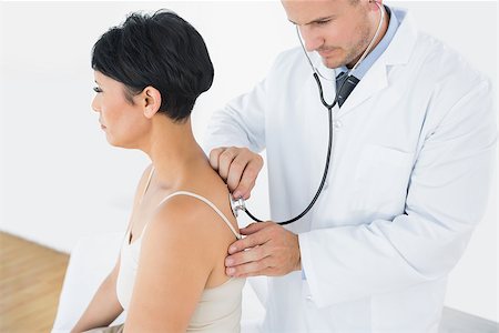 simsearch:400-05748252,k - Doctor using stethoscope on back of female patient in clinic Stock Photo - Budget Royalty-Free & Subscription, Code: 400-07335307