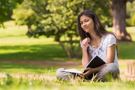 Portrait of a young woman with book and pen sitting in the park Stock Photo - Budget Royalty-Free & Subscription, Code: 400-07336795