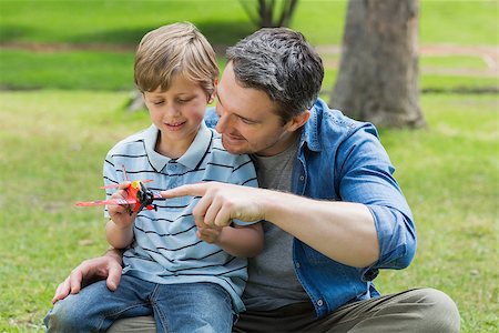 Young boy with toy aeroplane sitting on father's lap at the park Photographie de stock - Aubaine LD & Abonnement, Code: 400-07336931