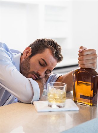 Drunk businessman clutching whiskey bottle asleep at the local bar Stock Photo - Budget Royalty-Free & Subscription, Code: 400-07337255