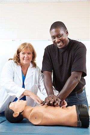 simsearch:400-07411030,k - Adult first aid or EMT student practicing CPR on a dummy, with the help of a doctor or nurse.  Vertical with room for text. Stock Photo - Budget Royalty-Free & Subscription, Code: 400-07411023