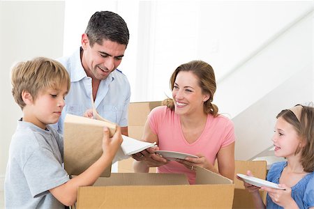 Family of four unpacking cardboard box in new house Stock Photo - Budget Royalty-Free & Subscription, Code: 400-07468402