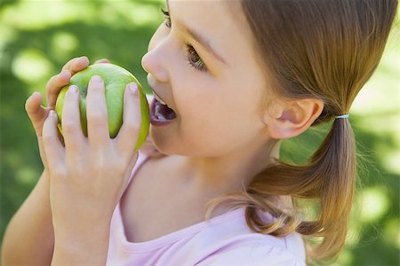 Close-up of a pretty young girl eating apple in the park Stock Photo - Budget Royalty-Free & Subscription, Code: 400-07474933