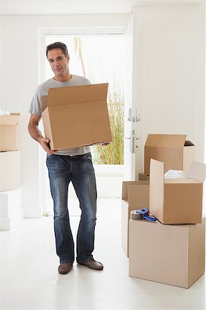 simsearch:400-07930718,k - Full length portrait of a smiling man carrying boxes in new house Stock Photo - Budget Royalty-Free & Subscription, Code: 400-07475262