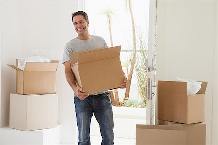 simsearch:400-07930718,k - Portrait of a smiling man carrying boxes in new house Stock Photo - Budget Royalty-Free & Subscription, Code: 400-07475263