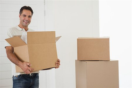 simsearch:400-07930718,k - Portrait of a smiling man carrying boxes in new house Stock Photo - Budget Royalty-Free & Subscription, Code: 400-07475270