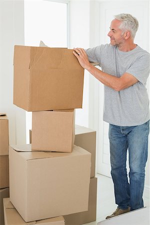 simsearch:400-07927836,k - Smiling man looking at cardboard moving boxes in new home Stock Photo - Budget Royalty-Free & Subscription, Code: 400-07475966