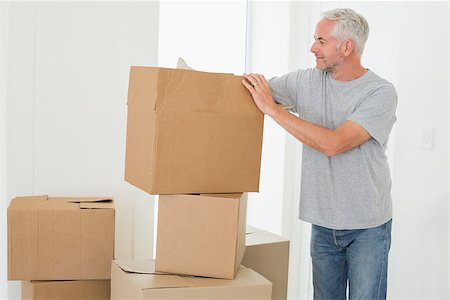 simsearch:400-07930718,k - Smiling man looking at cardboard moving boxes in new home Stock Photo - Budget Royalty-Free & Subscription, Code: 400-07475967