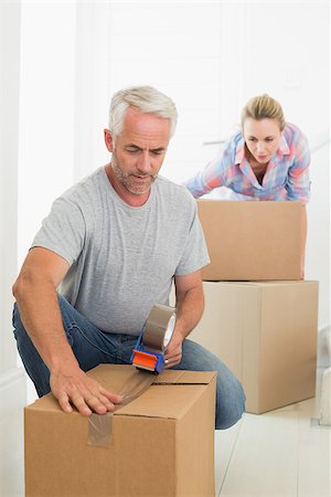 simsearch:400-07927836,k - Happy couple sealing cardboard moving boxes in their old home Stock Photo - Budget Royalty-Free & Subscription, Code: 400-07476004