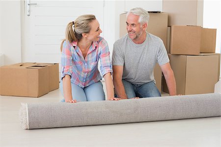 simsearch:400-07927836,k - Happy couple rolling out new rug in their new home Stock Photo - Budget Royalty-Free & Subscription, Code: 400-07476015