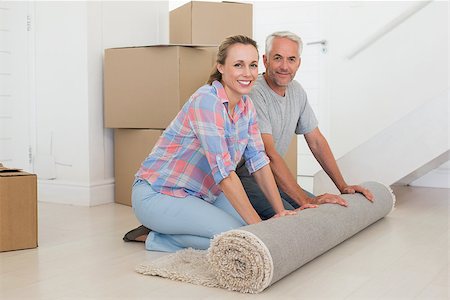 simsearch:400-07927836,k - Happy couple rolling out new rug in their new home Stock Photo - Budget Royalty-Free & Subscription, Code: 400-07476017