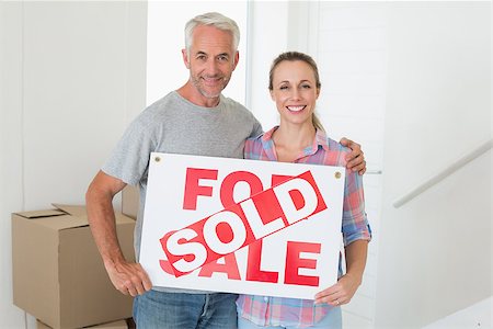 simsearch:400-07927836,k - Happy couple standing and holding sold sign in their new home Stock Photo - Budget Royalty-Free & Subscription, Code: 400-07476011