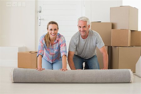 simsearch:400-07927836,k - Happy couple rolling out new rug in their new home Stock Photo - Budget Royalty-Free & Subscription, Code: 400-07476020