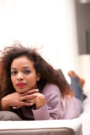 beautiful afro american woman staring at camera lying on a sofa Stock Photo - Budget Royalty-Free & Subscription, Code: 400-07479042