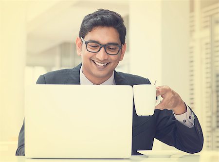 Young Asian Indian businessman using a notebook computer or laptop during office break at cafe, relaxing with a cup of coffee. India male business man, in vintage retro effect. Stock Photo - Budget Royalty-Free & Subscription, Code: 400-07470855